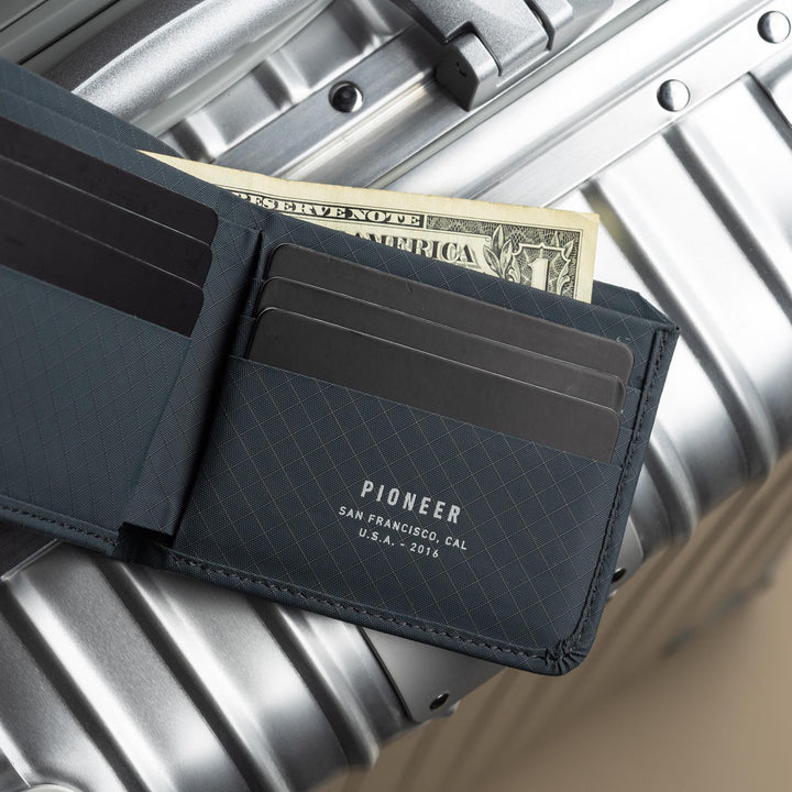 Pioneer Division Billfold Slate open on suitcase #color_slate-3xd